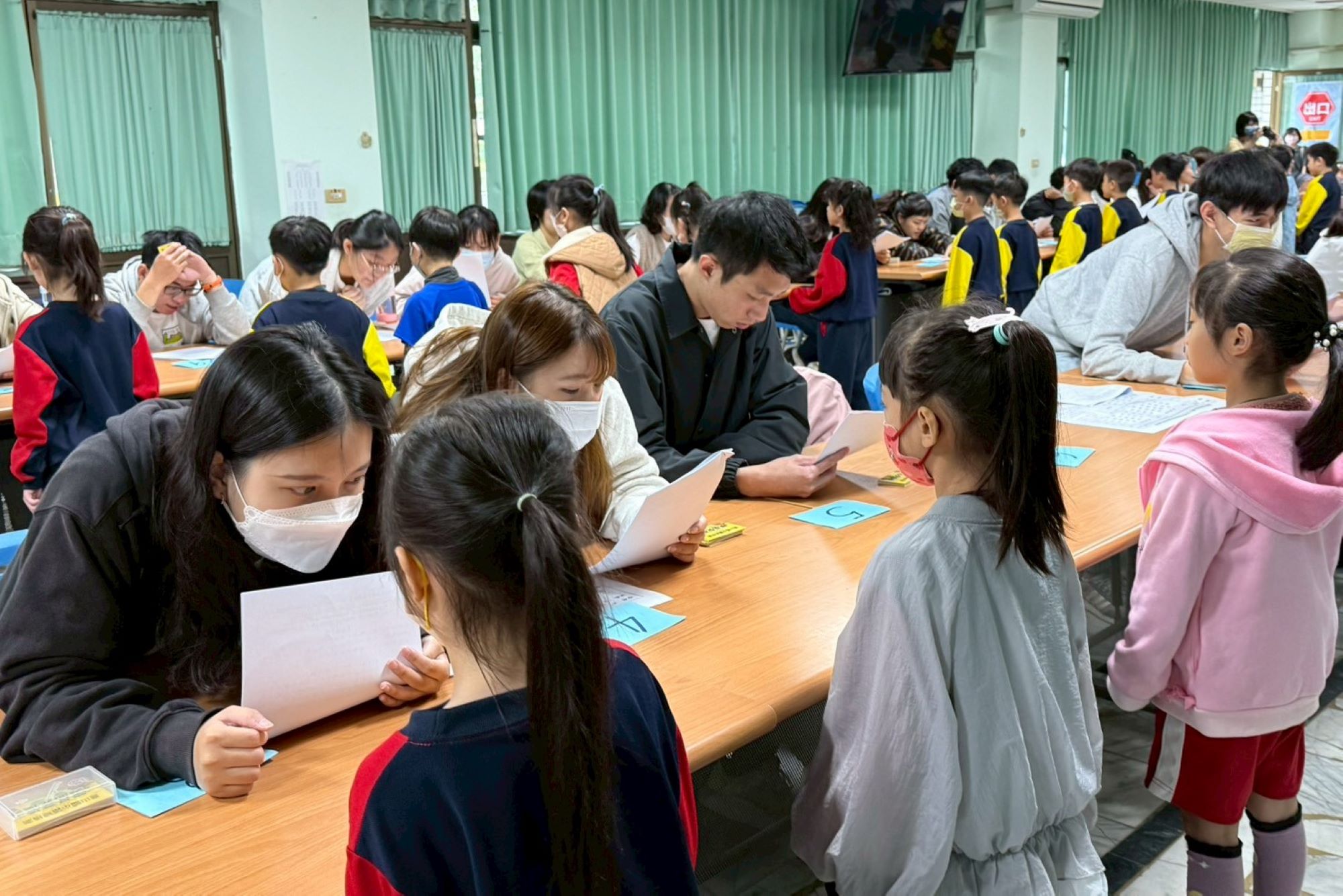 南大師資生於讀經檢測現場引導學童應試,近距離觀察學習表現與教學互動。