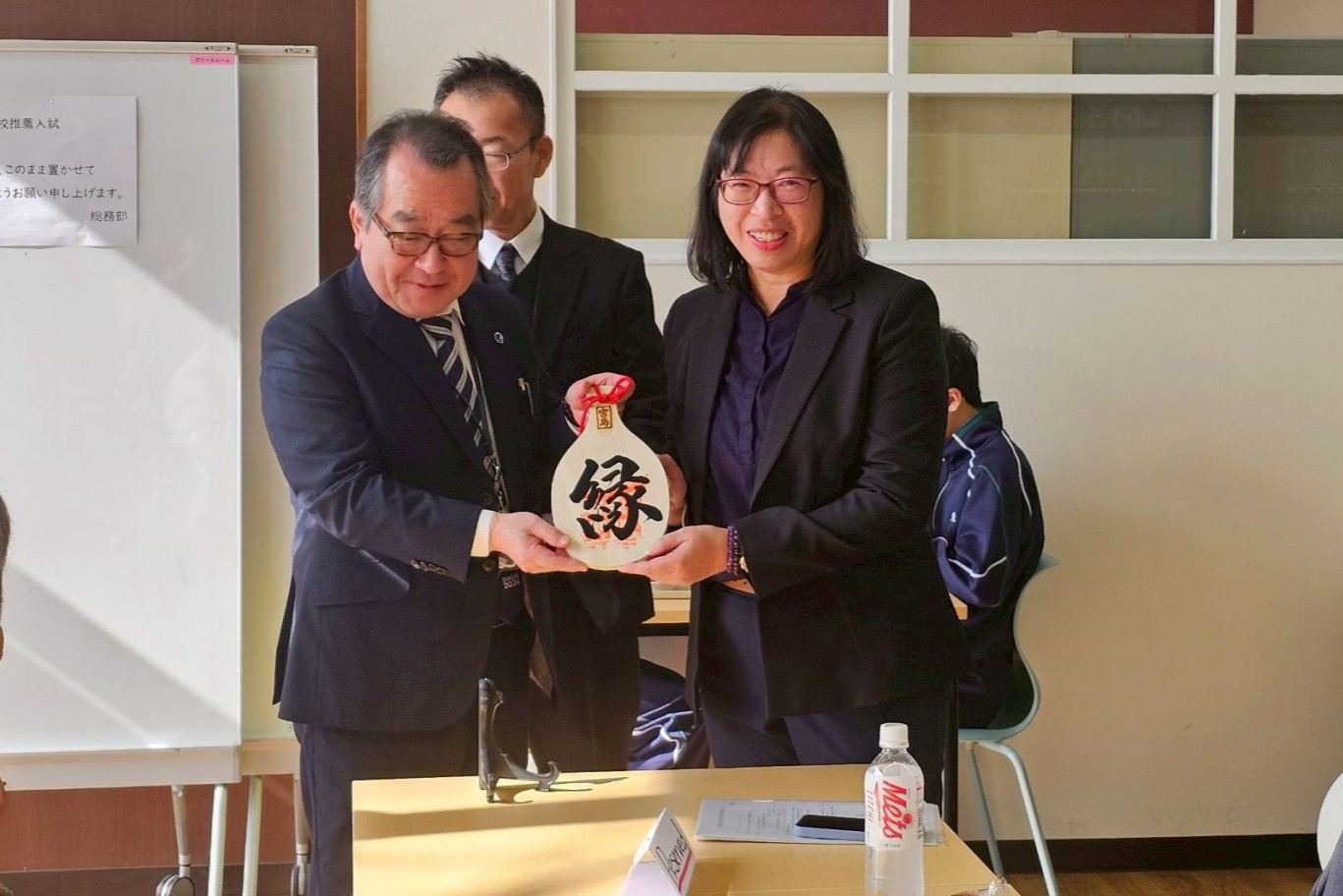 南大文資系與廣島修道大學附設高中代表交換紀念禮品,象徵臺日教育交流情誼與文化對話的深化。
